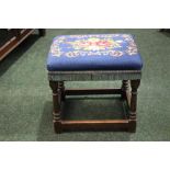 AN OAK JOINT FOOT STOOL, with stuffed over top, having needlepoint floral cover, 16" x 13" x 15"