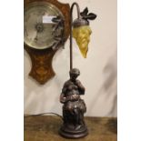 A TABLE LAMP, in the form of a seated lady reading a book, with foliage detail to the base, 22" tall