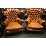 A PAIR OF TAN COLOURED LEATHER WING BACK ARMCHAIRS, button backs, raised on carved cabriole legs,