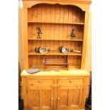 A PINE DRESSER, with 3 open shelves, over 2 drawers, over 2 door cabinet, raised on platform base