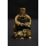 A NETSUKE OF A MAN HOLDING A SWORD, with a foot on the top of another man, 2" tall approx