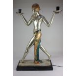 An Art Deco style chrome metal figural table lamp formed as a semi-nude dancer holding aloft two