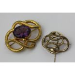 A mid 19th century amethyst brooch in tubular scroll mount, and a gilt metal example