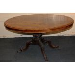 A Victorian walnut dining table with oval tilt-top on baluster stem and four carved outswept legs to