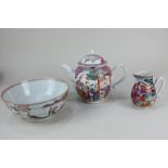 A Chinese porcelain teapot, milk jug and slop bowl, each decorated with figures in gardens and