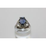 A sapphire and diamond ring, the oval cut stone eight claw set within six small diamonds in 18ct