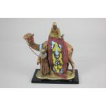 A 20th century painted spelter table lighter depicting two Arab carpet sellers with a camel, on