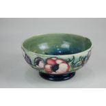 A Moorcroft circular pottery bowl decorated with anemones on green and blue graduated ground,