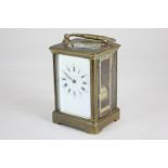 A brass and bevelled glass repeater carriage clock striking on a gong, the white enamel dial with