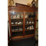 An oak bookcase with fluted frieze above and below twin panel glazed doors enclosing three