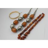 A Middle Eastern silver mounted amber necklace, an amber bead necklace, a gold plated bangle