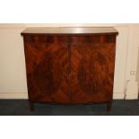 A reproduction bow front inlaid mahogany cabinet with crossbanded top, above two oval flame panel