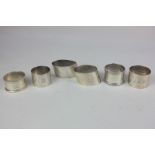 A pair of George V silver napkin rings, sloping oval shape with engraved initials, and four other