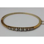An Edwardian pearl and diamond bangle in 15ct gold