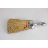 A Continental white metal handled table brush with embossed scroll design, marked sterling, 26.5cm