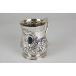 A George II silver mug with scroll handle, later embossed floral and scroll decoration, with