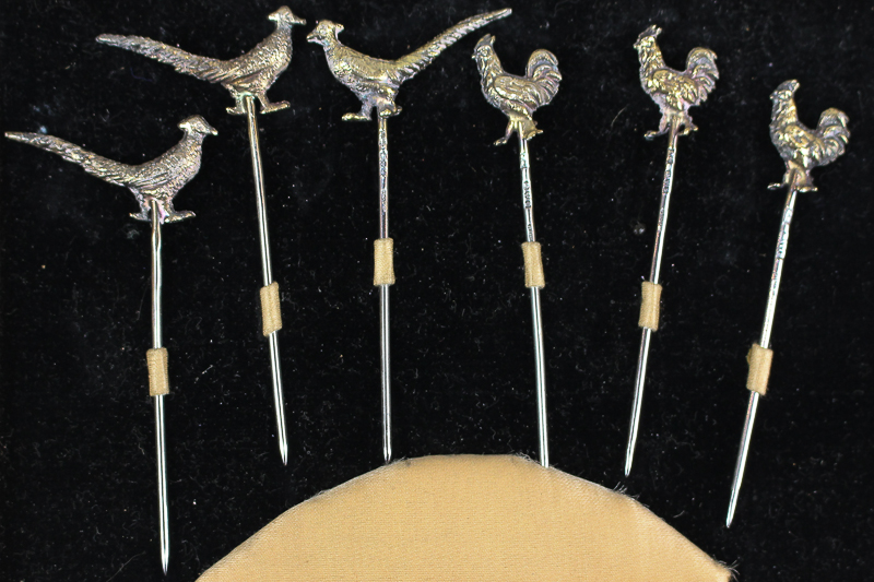 A cased set of six George V silver gilt stick pins, with three terminals in the form of cockerel,