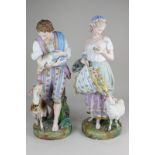 A pair of large bisque porcelain figures of a shepherd and a shepherdess, with sheep and goat,