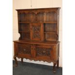 A carved oak dresser raised back with shelves and panelled cupboard carved with sea creatures, on