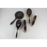 A George V silver and tortoiseshell dressing table set of two pairs of brushes and a hand mirror,