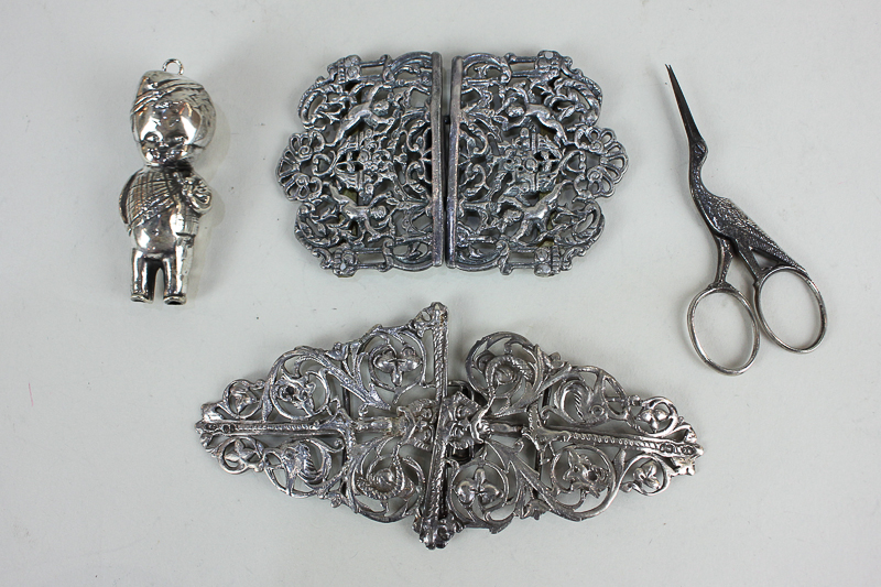 Two silver plated nurse's buckles with pierced designs (one a/f), a silver plated baby's rattle, and