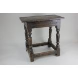 An oak jointed stool with carved frieze, on turned legs with low supporting stretcher