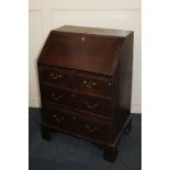 A George III small oak bureau with fall enclosing pigeon holes and small drawers over two short