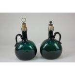 A pair of late 19th / early 20th century green glass decanters with handles, of flattened oval form,