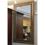 A composition wall mirror with floral and foliate decorated gilt painted frame, bevelled glass