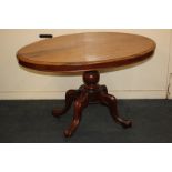 A 19th century fruit wood oval tilt-top table, baluster stem on outswept legs and castors, 118cm