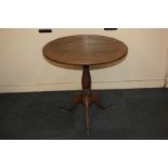 An oak tea table with circular tilt-top, turned baluster stem on outswept tripod legs, 66.5cm