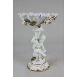 A 19th century porcelain centrepiece, the scalloped cornucopia with bocage roses, on figural support