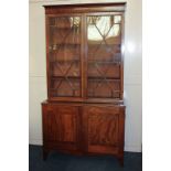 A 19th century mahogany bookcase with two glazed panel doors enclosing four shelves, the later