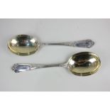 A pair of Victorian silver serving spoons with gilt bowls and floral scrolling design, John