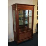 A French style gilt metal mounted display cabinet with glazed panel door enclosing two glass shelves