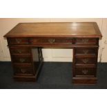 A Victorian oak pedestal desk with leather inset rectangular top and an arrangement of nine drawers,