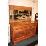 An Arts and Crafts Liberty style carved oak sideboard with two drawers with brass ring and strap