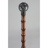A Victorian pewter mounted cane walking stick modelled as a grotesque man's face with irritating fly