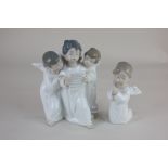 A Lladro figure group of three winged children singing from a hymn sheet, 19cm, together with a