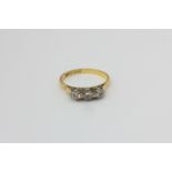A diamond three-stone ring, the uniform brilliant cuts claw set in 18ct white on yellow gold