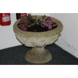 A pair of stone composition garden urn planters cast with shells and foliage, on pedestal bases,