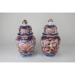A pair of Japanese Imari pottery jars and covers depicting birds amongst foliage (a/f), 28cm high