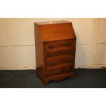 A small yew wood bureau with cross-banded fall front enclosing fitted interior of drawers and pigeon