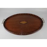 An Edwardian inlaid oval serving tray with two brass handles, raised striped border and shell design