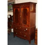 An early 19th century inlaid mahogany press cupboard, moulded cornice with central brass inlay above