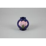 A miniature Moorcroft magnolia globular vase decorated with pink flowers on blue ground, 5cm