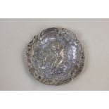 A Victorian silver embossed pin dish depicting a cherub playing a pipe, import mark, David Bridge,