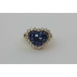 A sapphire and diamond ring, heart shaped, the central panel set with square cut sapphires within