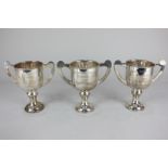 A set of four George V silver twin handled trophy cups on circular pedestal bases, each with