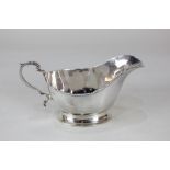A George VI silver sauce boat, faceted form on oval base with scroll handle, maker Mappin & Webb,